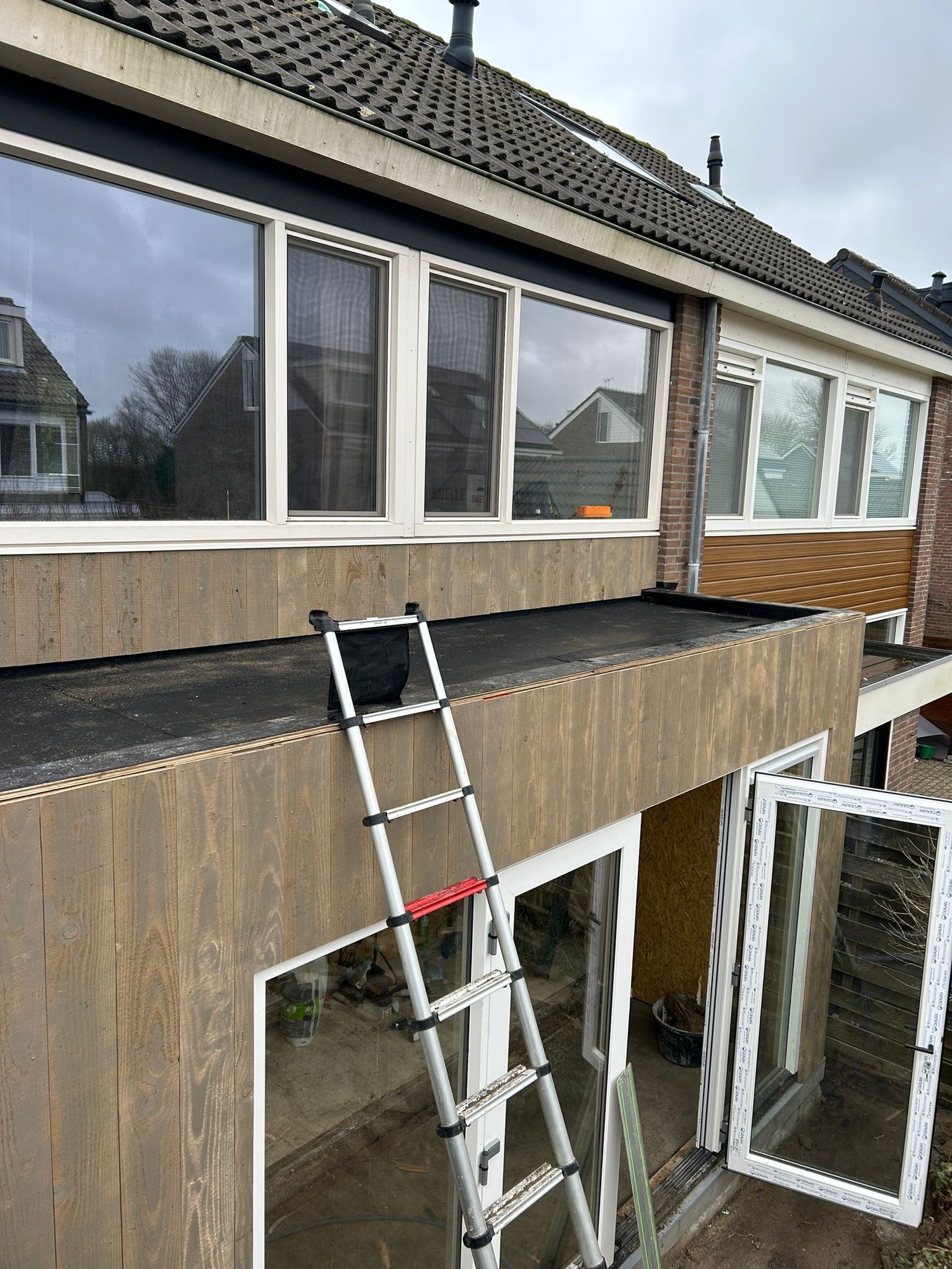 Aansluiting van het platte dak van een prefab aanbouw op de bestaande woning